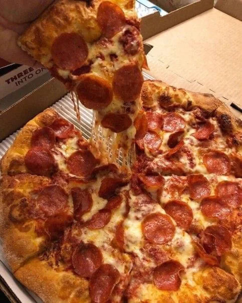 Pizza de pepperoni con una porción levantada y queso fundido
